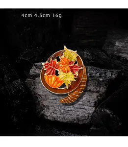 Detail shot of vintage maple leaf enamel brooch in autumn colors on charcoal background