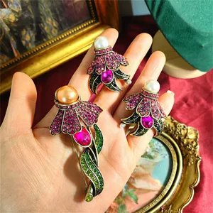 Dettaglio ravvicinato di spille a fiore vintage con cristalli rosa e perle nella mano