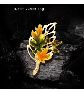 Close-up of vintage gold maple leaf enamel brooch with autumn yellow and green hues.