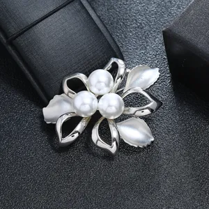 Detailed view of a vintage silver floral brooch featuring three elegant white pearls.