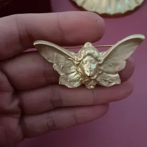 Nahaufnahme einer vintage mattgoldenen Brosche mit Schmetterlingsflügel-Reliefdesign