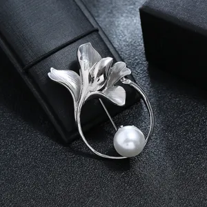 Detailed view of silver flower and leaf brooch with an elegant white pearl accent