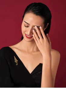 Detailed view of an elegant gold-toned crystal umbrella brooch worn on a black dress