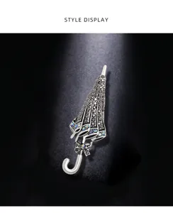 Detailed close-up of a vintage style umbrella brooch with black and iridescent crystals.