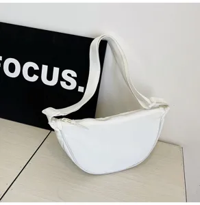Detalle de un bolso de media luna de nailon blanco minimalista con una correa ancha ajustable