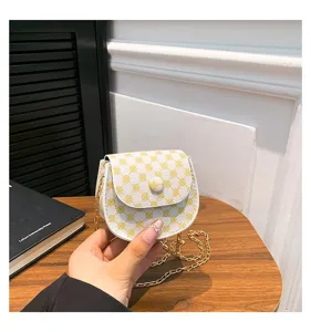 Vista detallada de un mini bolso bandolera blanco y amarillo con una cadena de oro