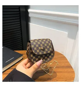 Detalle de un mini bolso bandolera marrón vintage con una elegante cadena dorada