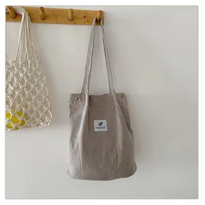 Detalle que muestra la textura de pana y la etiqueta de este bolso de mano.
