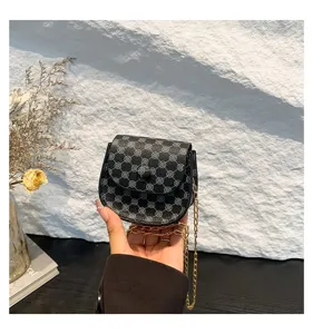 Detalle de cerca de un mini bolso bandolera vintage negro estampado con cadena