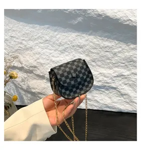Bolso de hombro vintage con estampado geométrico y cadena dorada sostenido en mano.