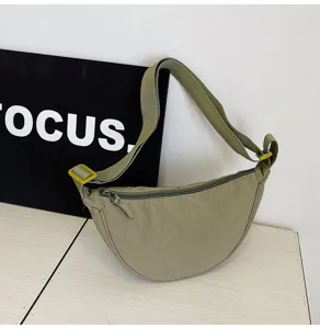Bolso bandolera de nailon verde salvia en forma de media luna con detalles de correa