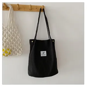 Detalle de un elegante bolso de pana negra colgado en un perchero de madera minimalista