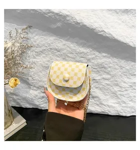 Primer plano de un bolso bandolera tipo silla con estampado floral amarillo y cadena metal