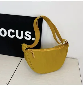 Detalle de bolso medialuna de nailon amarillo con correa ancha ajustable y cremallera