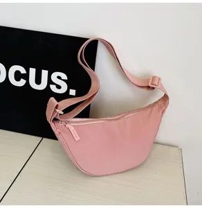 Detalle de bolso bandolera de media luna de nailon rosa con correa ajustable