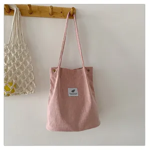 Imagen de detalle del bolso tote de pana rosa que muestra la tela texturizada y la etiqueta.