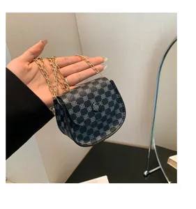 Detalle de un mini bolso bandolera retro con cadena dorada y estampado de tréboles