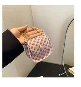 Vista detallada de un bolso de cadena rosa con estampado de trébol, sostenido a mano.