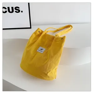 Primer plano de la textura de pana amarilla en un bolso de hombro de gran capacidad para mujer
