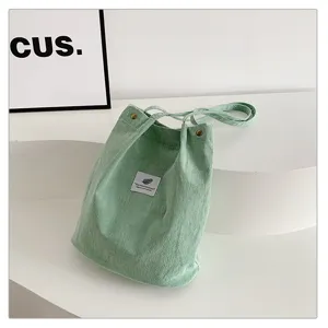 Detalle de primer plano de un bolso de hombro de pana verde claro minimalista