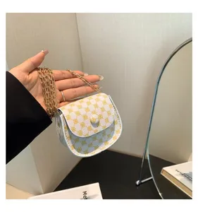 Primer plano de un mini bolso de cadena blanco con patrón vintage amarillo en mano