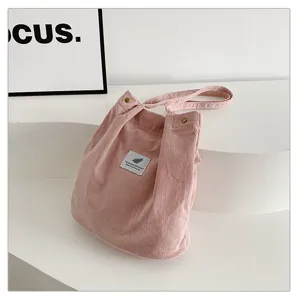 Primer plano del bolso tote de pana rosa con textura suave de canalé y etiqueta sencilla.
