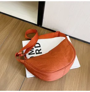 Vista detallada de un bolso bandolera tipo dumpling de nailon naranja vibrante muy moderno