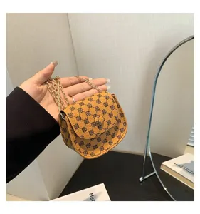 Detalle de un elegante bolso bandolera marrón retro con una cadena dorada.