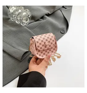 Primer plano de un bolso bandolera rosa con monograma y cadena dorada en la mano