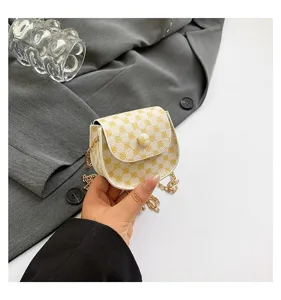 Primer plano de un mini bolso retro de cadena con patrones amarillos sostenido en la mano