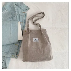 Primer plano de un bolso tote minimalista de pana marrón claro con una chaqueta.