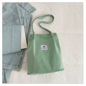 Bolso tote minimalista de pana verde claro con etiqueta y una chaqueta vaquera