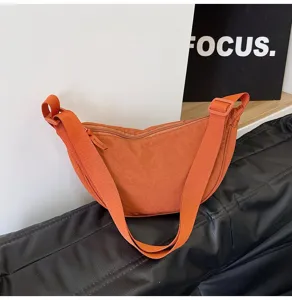Primer plano de un bolso de nylon naranja vibrante en forma de media luna.