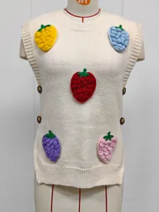 Detalle de fresas de ganchillo en 3D de colores sobre un chaleco de punto crema