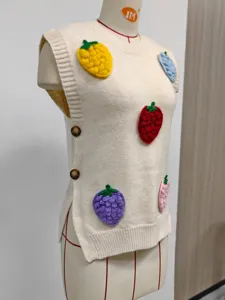 Detalle del chaleco de punto crema con fresas en 3D de colores y botones en el lateral.