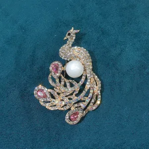 Detailed view of a vintage gold-toned peacock brooch with pink crystals and a large pearl.