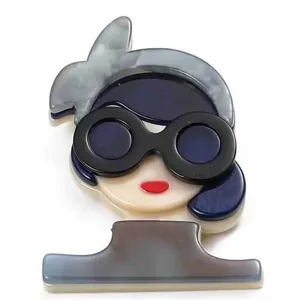 Detailed view of a vintage style acrylic brooch featuring a girl with sunglasses design