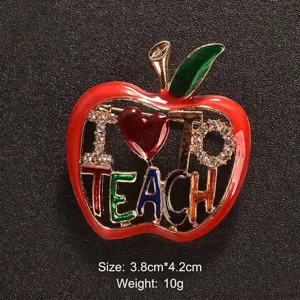 Dettaglio spilla mela rossa con scritta colorata 'I Love To TEACH' e piccoli cristalli.