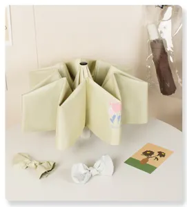 Close-up of a light green automatic tulip umbrella with decorative bow accessories.