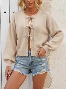 Close-up of women's knit cardigan featuring delicate front tie bows and long puff sleeves.