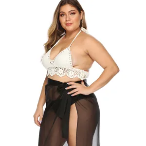 Detailansicht eines weißen Häkel-Bikini-Tops und eines schwarzen transparenten Strandrocks