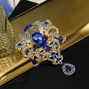 Exquisites Detail einer Vintage-Goldbrosche mit blauen Kristallen und Tropfenanhänger