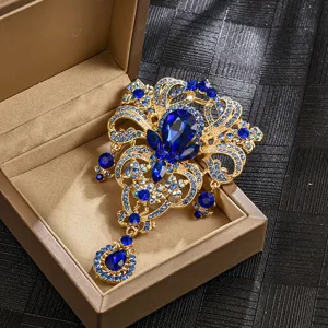 Detailansicht einer goldenen Kronen-Brosche mit blauen Kristallen in einer Schmuckschachtel