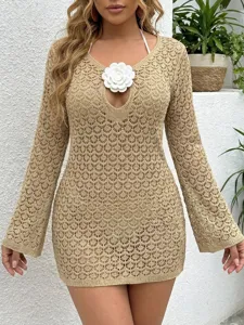 Vista dettagliata del copricostume beige all'uncinetto con un fiore bianco applicato