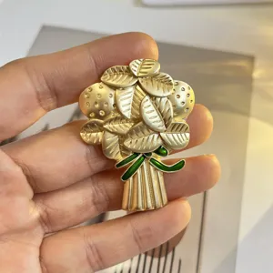 Makroansicht einer vintage mattgoldenen Blumenstrauß-Brosche mit grüner Schleife