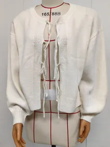Close-up detail of the cream white knitted cardigan with front tie bows and balloon sleeves.
