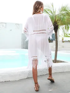 Detailed back view of a white crochet beach cover-up with elegant tassel trim and fringe.