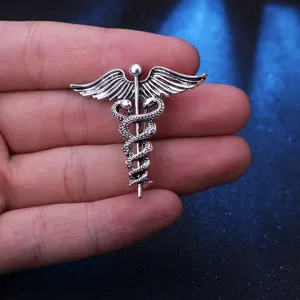 Nahaufnahme einer vintage Caduceus-Brosche in Silber mit geflügelten Schlangen.