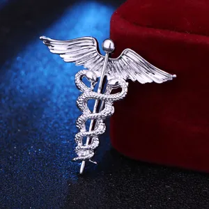 Detailansicht einer silbernen Caduceus-Brosche mit Engelsflügeln und zwei Schlangen