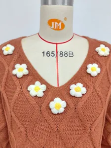 Detailed view of women's brown knit V-neck sweater featuring handmade floral crochet decor.